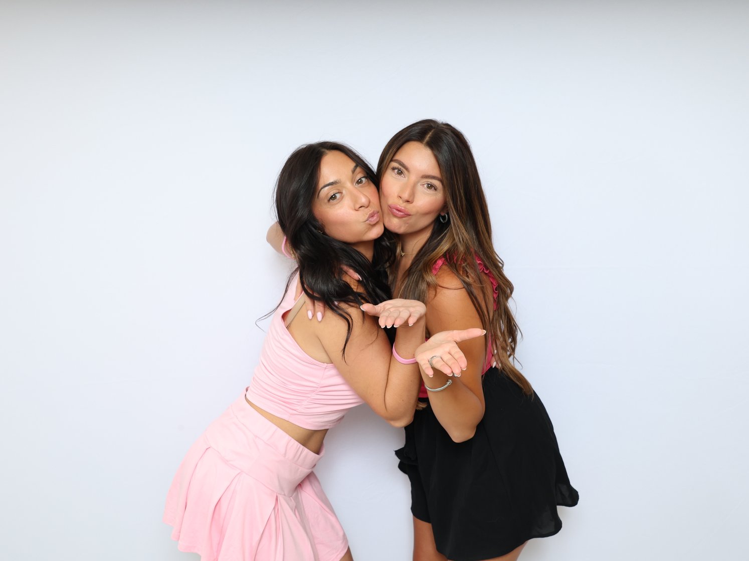 Two friends striking a playful pose on a white backdrop