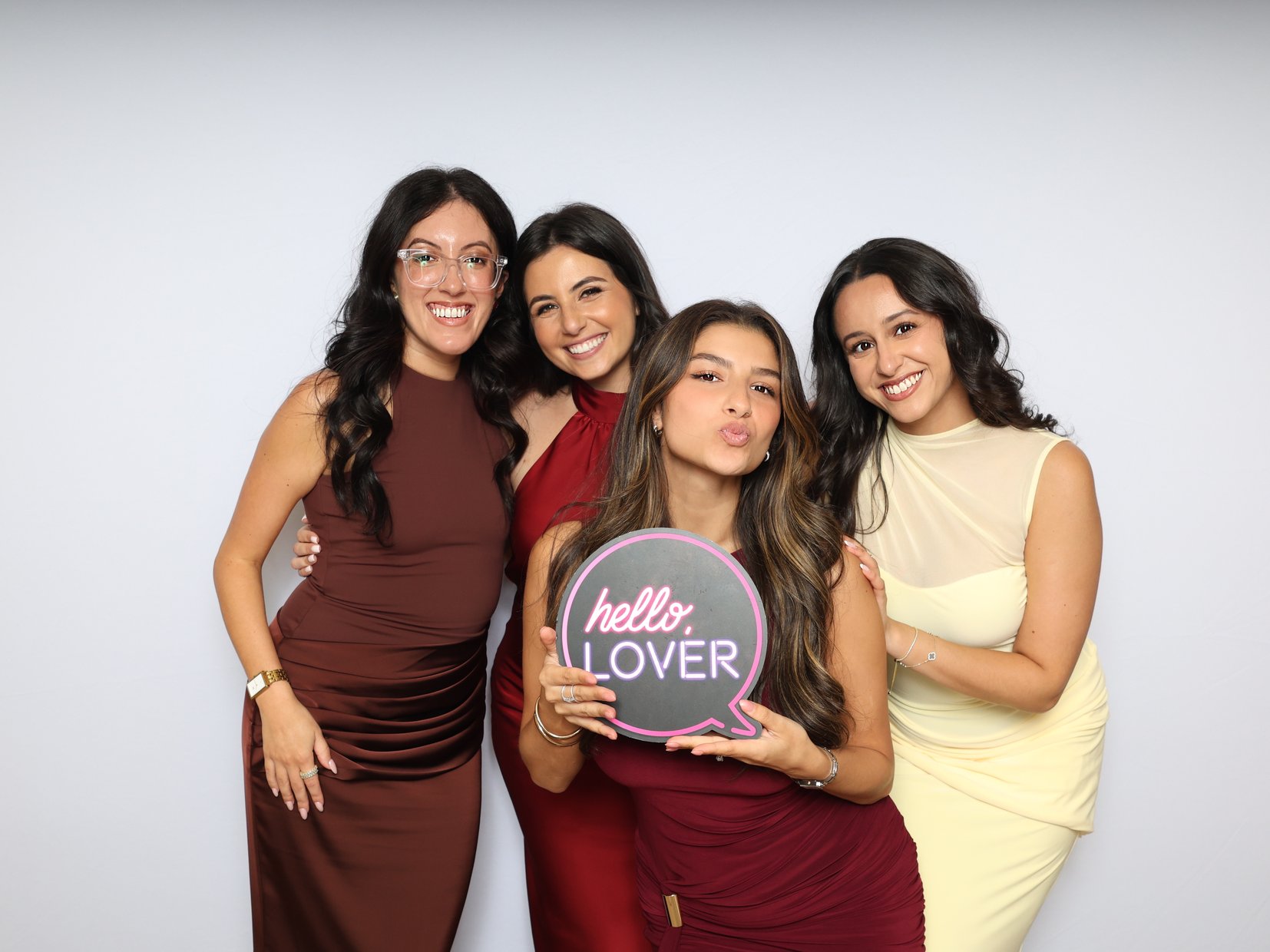 Friends posing with a round sign prop in front of a white backdrop