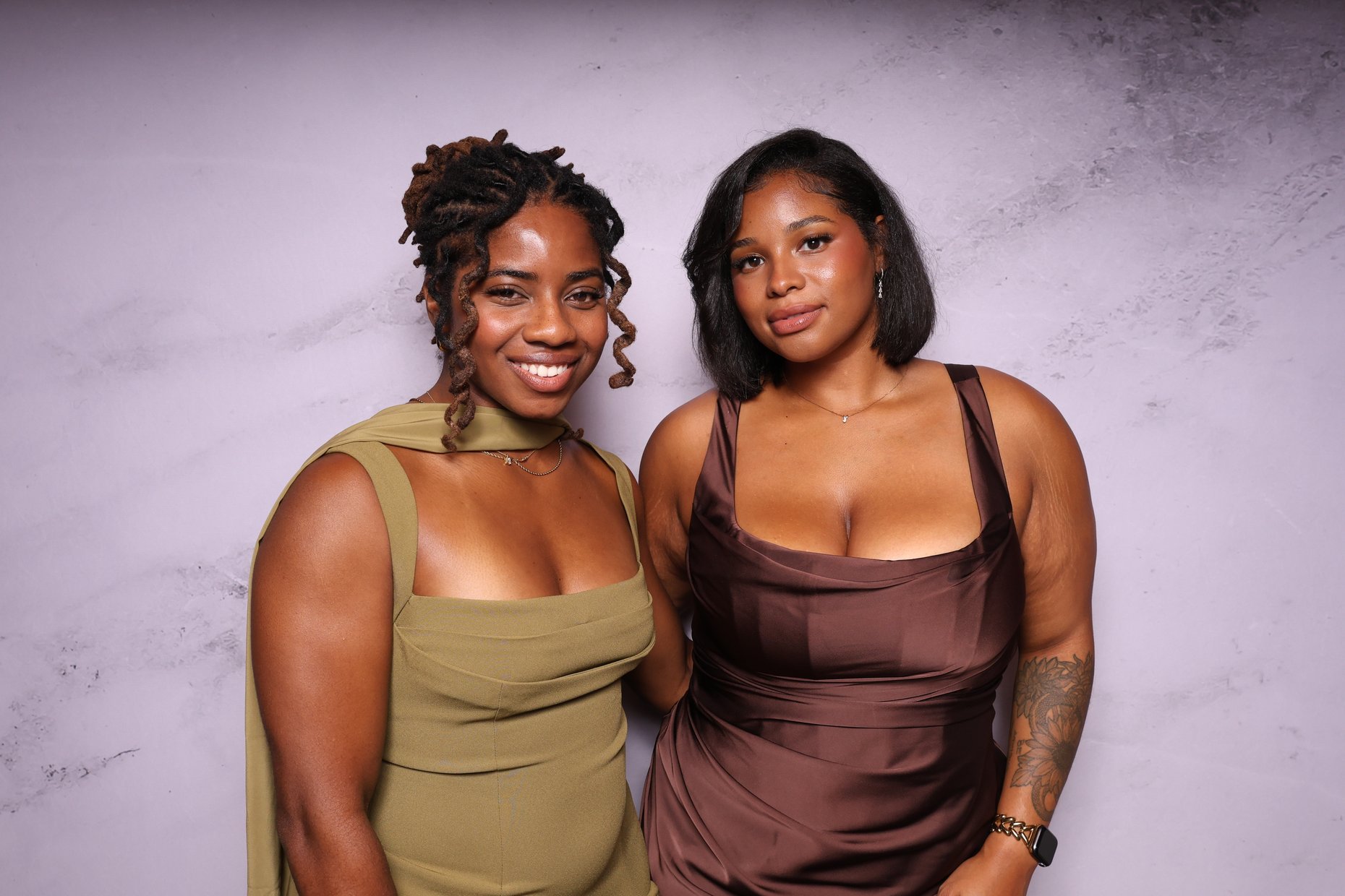 Two women posing in front of a marble backdrop